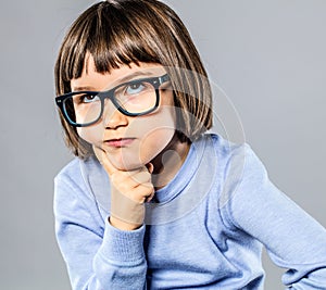 Beautiful kid playing Thinker with serious eyeglasses for intelligent solution