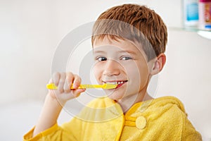 Beautiful kid preparing to brush their teeth wearing yellow bathrobes. closeup
