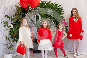 Beautiful kids friends with red balloons in the shape of a heart at the holiday