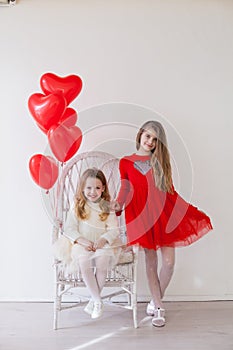 Beautiful kids friends with red balloons in the shape of a heart at the holiday