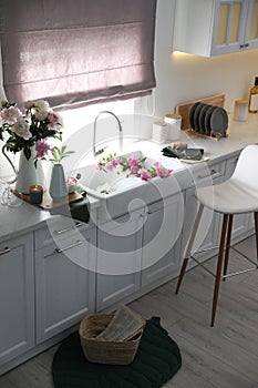 Beautiful kitchen interior with furniture and fresh peonies