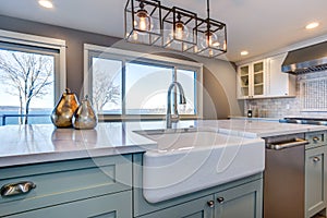 Beautiful kitchen room with green island and farm sink.