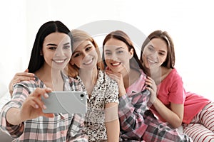 Beautiful ladies taking selfie on bed at pamper party. Women`s Day