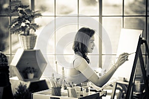 Beautiful lady Asian woman sitting and use a brush to pain picture in the room. Idea for hobby, relaxation or artist work from