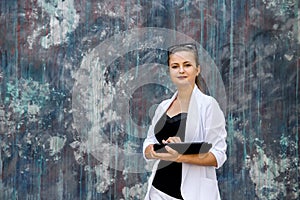 Beautiful lady in business suit holding tablet and posing on abstract background