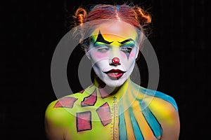 Beautiful lady with a face painting clown posing in the studio