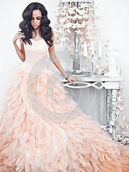 Beautiful lady in gorgeous couture dress in white interior