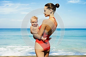 Beautiful lady with little baby-girl on the summer beach