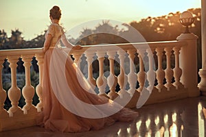 Beautiful lady in luxurious ballroom dress with tulle skirt and lacy top standing on the large balcony