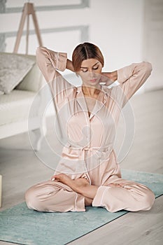 Beautiful lady is meditating on floor in her bedroom