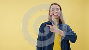Beautiful lady poining with forefinger over empty isolated yellow background