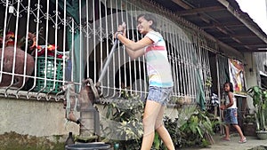 Beautiful lady pumps out water from a deep well hand held water pump