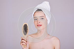 Beautiful lady after a shower holds a wooden comb in her hands