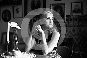 Beautiful lady sitting at a table, a black-and-white portrait in retro style.