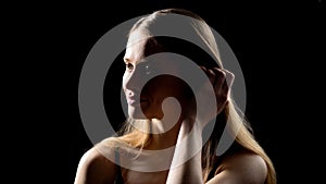 Beautiful lady taking hair away and smiling against dark background, innocence