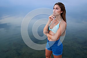 Beautiful lady on tropical island beach with flat mirror glassy water surface. Fashionable tanned woman with slim