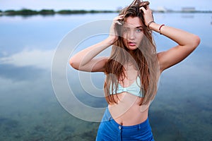 Beautiful lady on tropical island beach with flat mirror glassy water surface. Fashionable tanned woman with slim