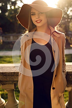 Beautiful ladylike woman in elegant fashion clothes posing at park