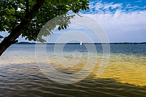 A beautiful lagoon with clear water. A lonely sailboat in the background. Sunny day. Holidays. Lake DzieÄ‡kowice, Poland