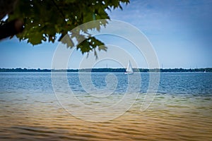 A beautiful lagoon with clear water. A lonely sailboat in the background. Sunny day. Holidays. Lake DzieÄ‡kowice, Poland