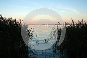 Beautiful lake landscape, yacht, and sunset. Blue waves, boat and horizon line on water. Beautiful background