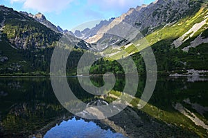 The beautiful lake Popradske pleso in the High Tatras in the evening sun with a reflection of the mountains. Slovakia