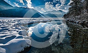 Beautiful lake reflecting the cloudy blue sky on a sunny winter day perfect for wallpapers