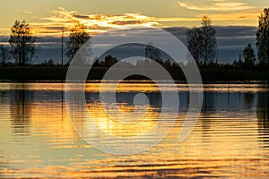 Beautiful lake at sunrise, golden hour sunrise, sunlight and grand cloud reflections on water, colorful dramatic sky at sunrise