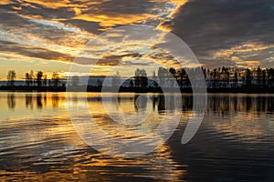 Beautiful lake at sunrise, golden hour sunrise, sunlight and grand cloud reflections on water, colorful dramatic sky at sunrise