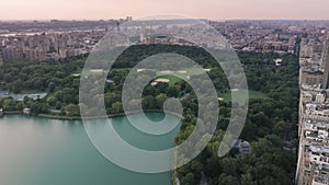 Beautiful lake surrounded by green park and buildings of Manhattan uptown in NYC