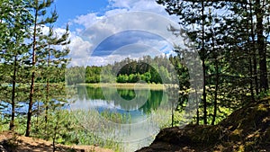 A beautiful lake surrounded by trees and a cloudy sky. The water is calm and the trees are lush and green