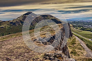 Beautiful landscape of Arthur`s Seat mountain in Scotland with path on the cliff and Edinburgh city in the background photo