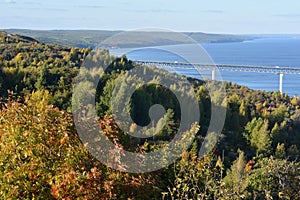 Beautiful landscape of autumn forest on the slope with bridge over the river on the background