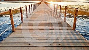 Beautiful landscape of calm ocean waves and long wooden pier. Amazing jetty at sea aagainst sunset over the mountains