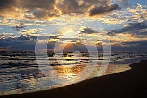 Beautiful landscape: cloudy sky and the sea reflects the sun, at sunrise or sunset