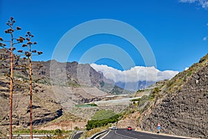 Beautiful landscape of a countryside tar road with a cloudy blue sky and copy space. Roadway with cars driving to