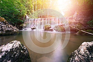 Beautiful landscape in Europe: Alpine River, waterfall and sunlight in the forest