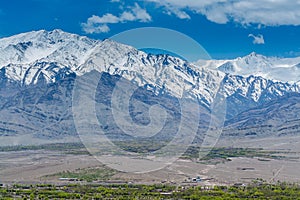 Beautiful landscape with fields of delta of Indus River, Tibetian buildings, Himalayas snow mountains, and blue sky,  in Ladakh,