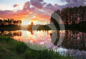 Beautiful landscape with fiery sunset over the lake