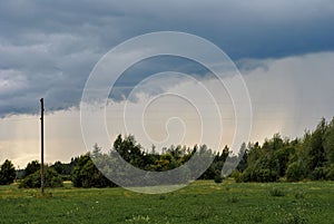 Beautiful landscape of a green field and trees on a stormy sunset