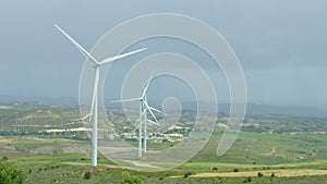 Beautiful landscape with green hills and rotating wind turbines, green energy