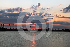 Beautiful landscape Harbor of Tallinn during sunrise. Cranes silhouettes against fiery, orange and red sky. seaport