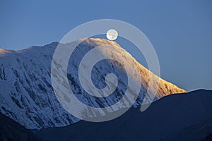 Beautiful landscape in Himalayas, Annapurna , Nepal. Full moon during a sunrise on the background of snow-capped mountains