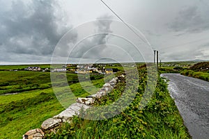 Beautiful landscape of the Irish countryside with a rural road and the village of Doolin in the background