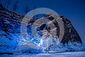 Beautiful landscape island Shaman Stone winter lake Baikal with transparent cracked blue ice. Concept travel Russia