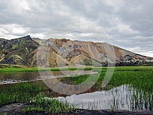 Beautiful landscape of Landmannalaugar geothermal area with river, green grass field and rhyolite mountains, Iceland