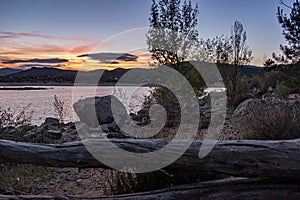 Beautiful landscape with a log on the seashore on the sunset background