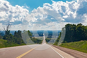 Beautiful landscape midday view of Canadian Ontario empty countryside road during sunny day with white clouds in blue sky.