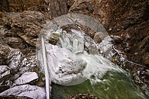 Landscape with a mountain river with small waterfalls in winter day in the canyon