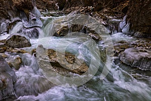 Landscape with a mountain river with small waterfalls in winter day in the canyon